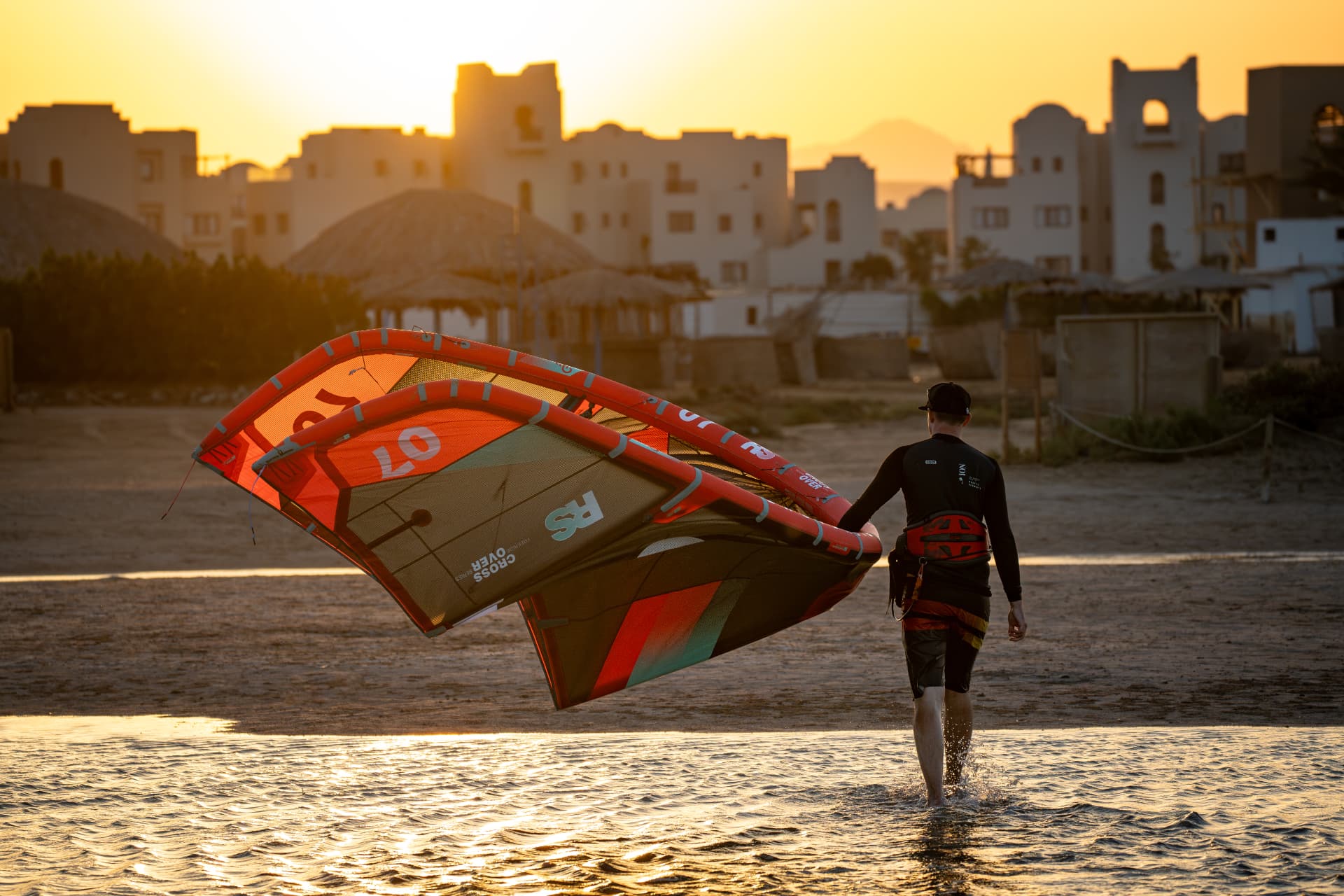 Rider marchant sur la plage avec son aile au coucher du soleil